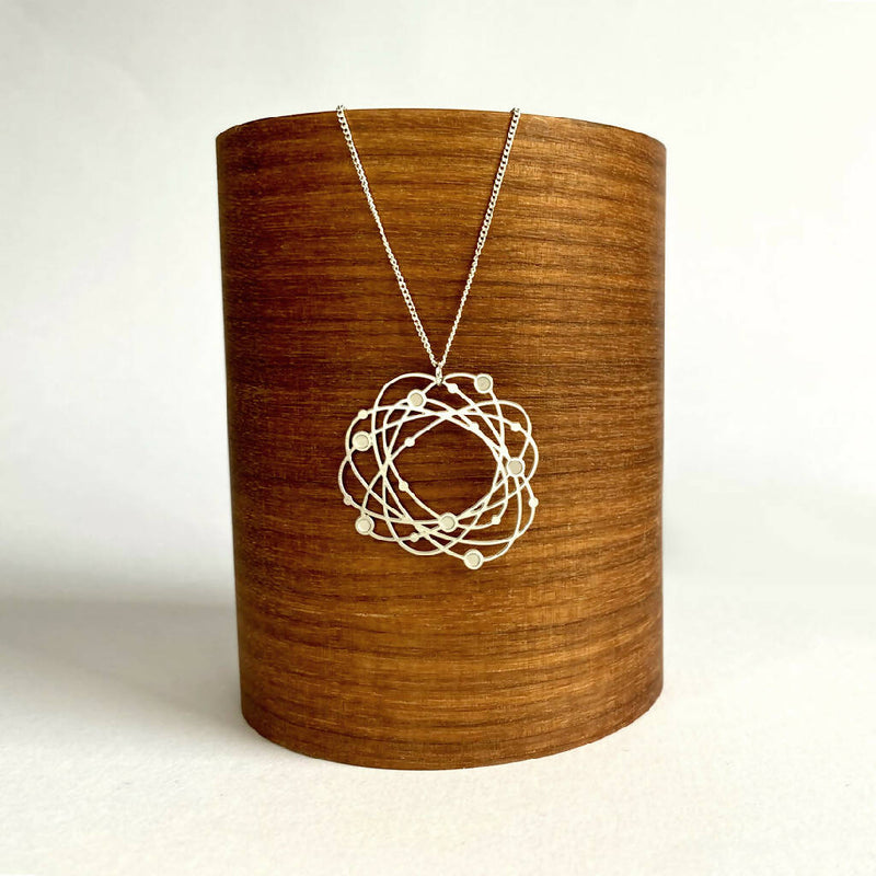 go-do-good-orbit-pendant-necklace-on-wood